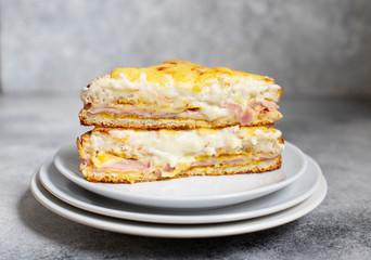 Sandwich with ham, cheese and bechamel sauce. A traditional french croque-monsieur sandwich served on a white plate. Gray background. Close-up. Front view. Space for text