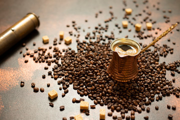 Turkish coffee concept. Copper coffee pot (Cezve), vintage coffee grinder, coffee beans and sugar on a dark vintage background. Close-up