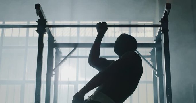 Cinematic slow motion shot of a professional young muscular shirtless african man is practicing shadow boxing work out in a gym.