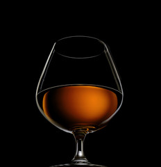 a glass of brandy on a black background