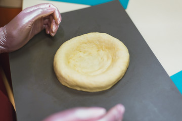 sculpt from dough buns and bread. the woman kneads the dough and makes round bread from it. A cook in gloves creates a tasty bakery product