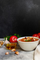 Traditional summer cold tomato soup gazpacho served in a white bowl. Tomatoes, garlic, basil, parsley, olive oil and croutons. Mediterranean, Spanish cuisine. Close-up. Black background. Copy space