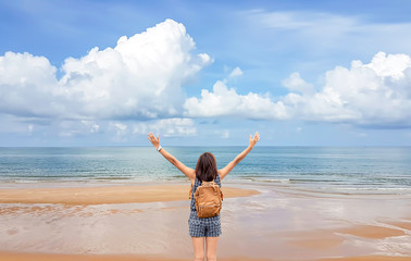 Women raise their arms and shoulder backpack on the beach  background sea and sky at Chanthaburi in Thailand.