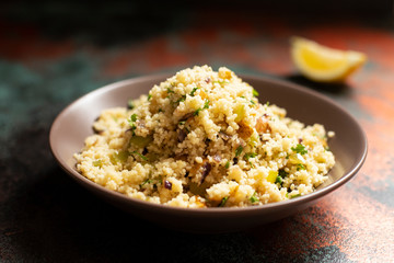 Traditional couscous with vegetables and herbs in a bowl. Levantine vegetarian salad. Lebanese, arabic cuisine. Close-up. Copy space