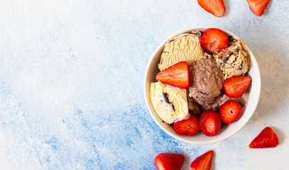 Fototapeta na wymiar Chocolate and vanilla ice cream in a white bowl with fresh strawberries. Light blue background. Top view. Copy space