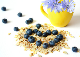 dry oatmeal, blueberries, yellow cup of chicory flowers in the background. Granola. Breakfast. The concept of a healthy diet, diet.