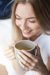 Renew your mind every morning. Close up of cheerful blonde girl drinking coffee in the morning
