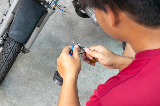 Mechanic Man Fix Or Repair Motorcycle In Garage Cutting Electric Wires With Cutting Pliers. Repair Or Maintenance Concept.