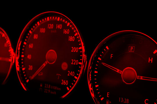 Close up shot of red speedometer in a car. Car dashboard. Dashboard details with indication lamps.Car instrument panel. Dashboard with speedometer, tachometer, odometer. Car detailing.