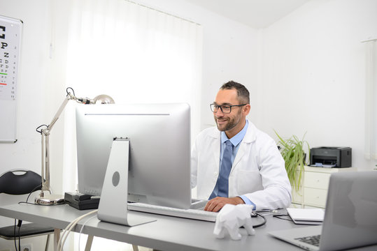 Portrait Of A Handsome Man Male Doctor In Medical Practice Office Working On Computer