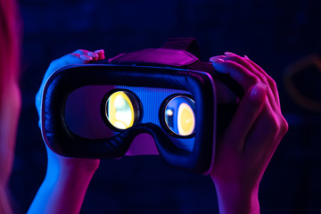 Female hands hold 3d 360 vr headset glasses goggles in futuristic purple neon light, girl gamer...