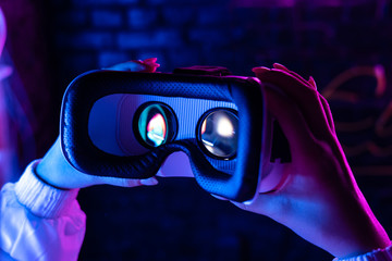 Female hands hold 3d 360 vr headset glasses goggles in futuristic purple neon light, girl gamer...