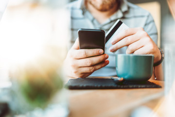 man using smart phone and credit card in local cafe. shopping online with credit card