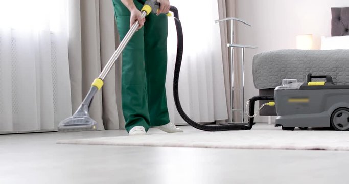 Professional janitor cleaning carpet in bedroom, closeup