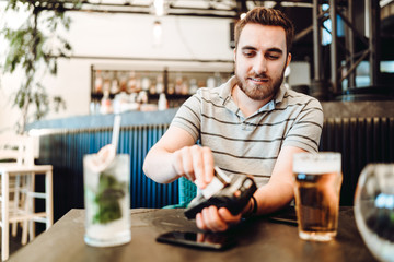 Portrait of man paying at restaurant using credit card and wireless terminal