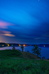Beautiful long exposure landscape view of the mountain lake Turgoyak, Russia with cloudy sky and summer house on the hill in summer night