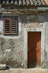 Fototapeta na wymiar Wooden door and window on stone wall, building facade, Pag, Croatia