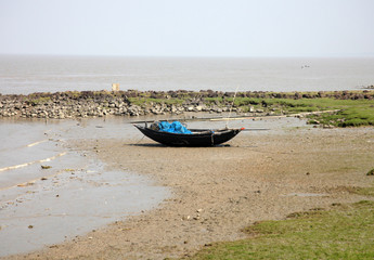 Boats of fishermen stranded in the mud at low tide on the coast of Bay of Bengal, India