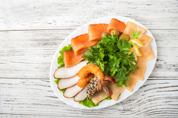 Fish platter in a white plate close-up. Snack of fish with lemon and olives copy space.