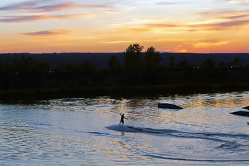 Naklejka premium silhouette of a surfer on the water at sunset