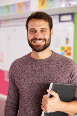 Portrait Of Male Elementary School Teacher Standing In Classroom