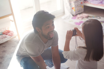 Vater hockt vor dem Kind und schneidet Grimassen für ein Foto