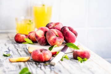 Reife und saftige Pfirsiche auf dem hellem tisch mit frischem Saft im Hintergrund
