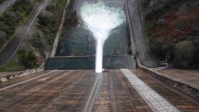 Vista cenital de enorme chorro de agua saliendo  en el punto de evacuacion de una presa o dique de embalse