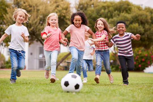 Group Of Children Playing Football With Friends In Park