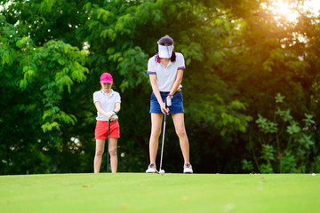 woman golf player in action being prepare and setup address to hit the golf ball away from T-OFF to...