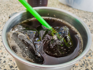 Close up cola drink wich ice in a glass of stainless steel