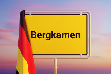 Bergkamen. Gelbes Schild/Ortsschild. Flagge von Deutschland hängt darüber. Himmel mit Sonnenuntergang oder Sonnenaufgang