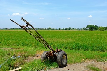 Idle walking tractor on rice field ready to be used at the beginning of rice growing season.