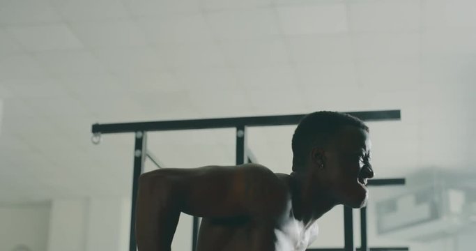 Cinematic slow motion shot of a professional young muscular shirtless african man is practicing shadow boxing work out in a ring. 