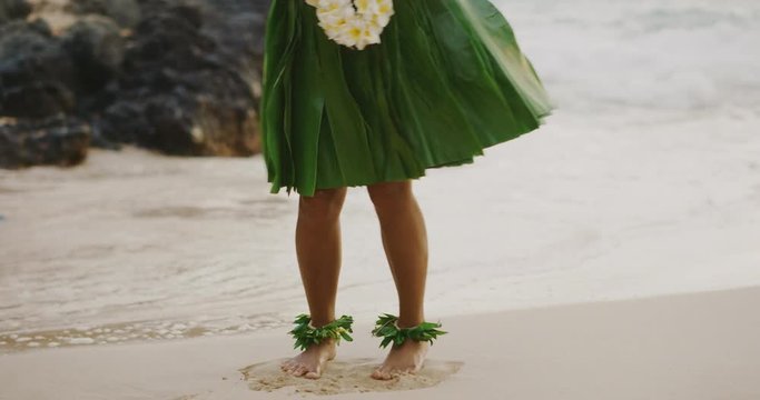 Shot of a Hula dancer's legs with a ti leaf skirt and ankle haku lei's, Hawaiian island hula dancing on the beach in slow motion