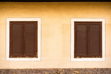 Two wooden windows with brown shutters on Austrian house