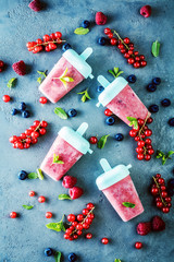 top view of delicious sweet ice lollies and fresh ripe berries on grey surface