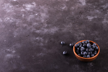 Freshly picked blueberries in wooden bowl on rustic table. Bilberry on stone background. Blueberry antioxidant. Concept for healthy eating and nutrition