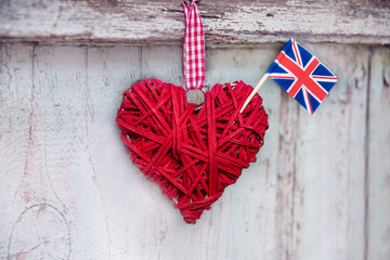 Decorative heart made of straw with the flag of the United Kingdom on the background of a wooden textured fence
