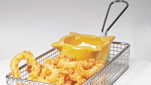Rings of calamari whit white sauce mayonnaise whit ginger - calamares fritos tipical spanish street food - squid whit white screen rotating in movement, fried recipe Tapa de Calamares