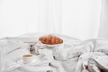 fresh croissant with coffee in white bed at morning