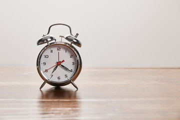 silver alarm clock on wooden brown table isolated on grey