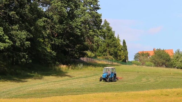 Blue tractor turn dry grass, hay near forest, Rural scene, Czech landscape