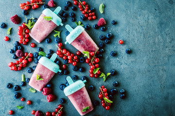 top view of delicious sweet ice lollies and fresh ripe berries on grey surface