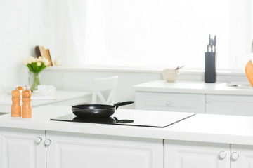 Obraz na płótnie Canvas modern kitchen with white counter, cooker and frying pan
