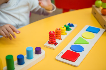 close-up of a child's hands collecting a multicolored wooden educational toy sorter