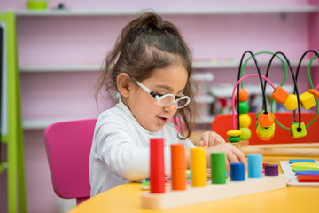 child girl with glasses for vision plays in educational classes
