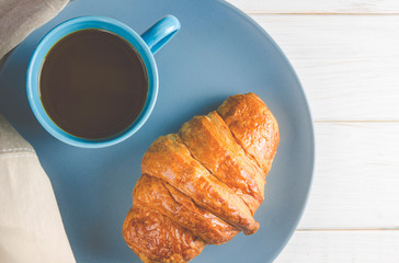 Fresh ruddy croissants with berries lie on a wooden table next to fresh black currant berries, red currants