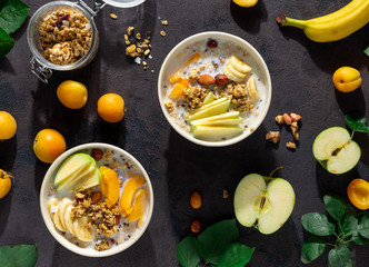 Granola breakfast with fruits, nuts, milk and peanut butter in bowl on a white background. Healthy breakfast cereal top view