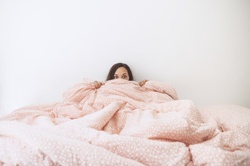 Portrait of a beautiful girl who covers her face with a blanket.